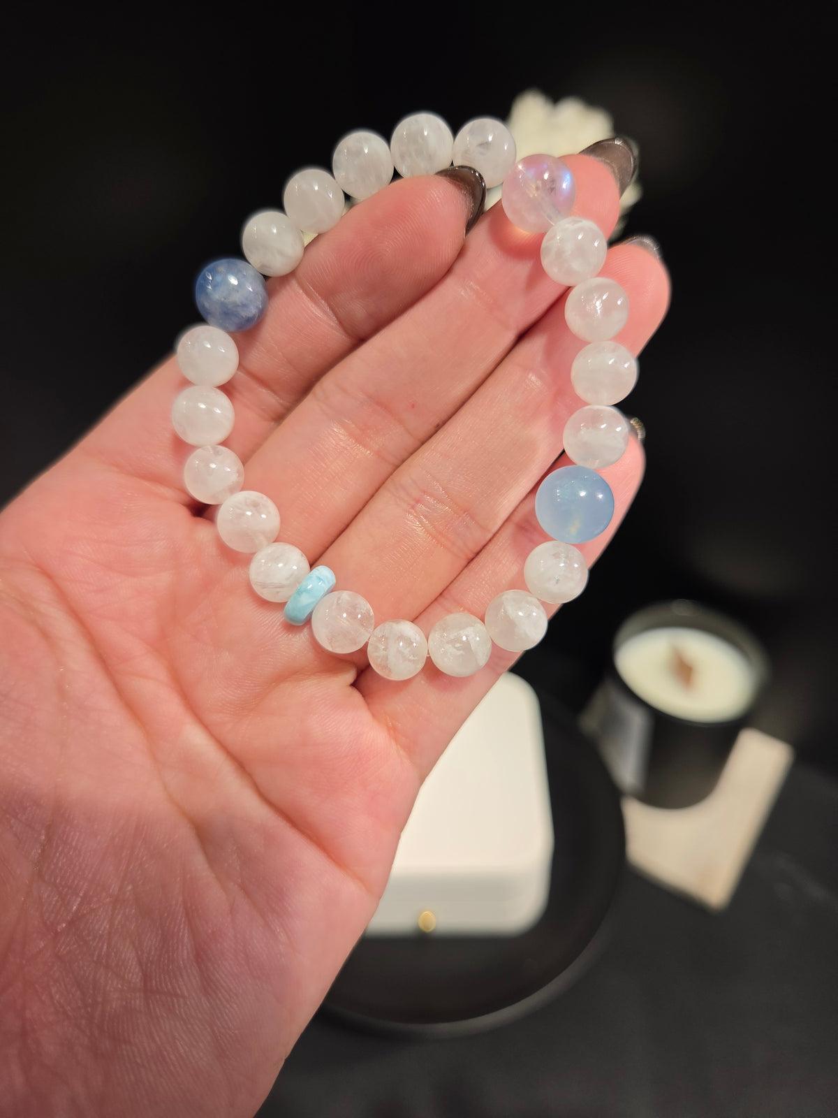 Hand holding light luxury white moonstone and aquamarine beaded crystal bracelet showing bead details