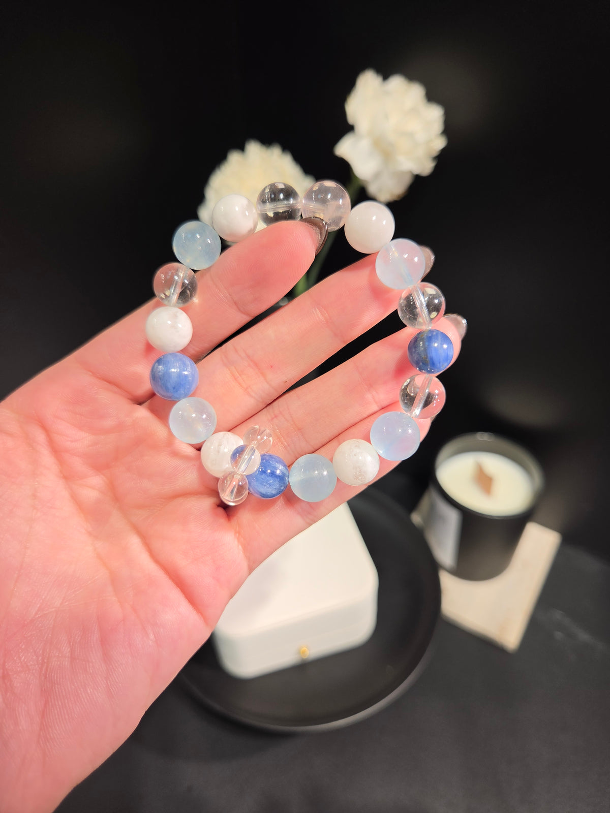 Hand holding light luxury kyanite and aquamarine beaded crystal bracelet with butterfly charm