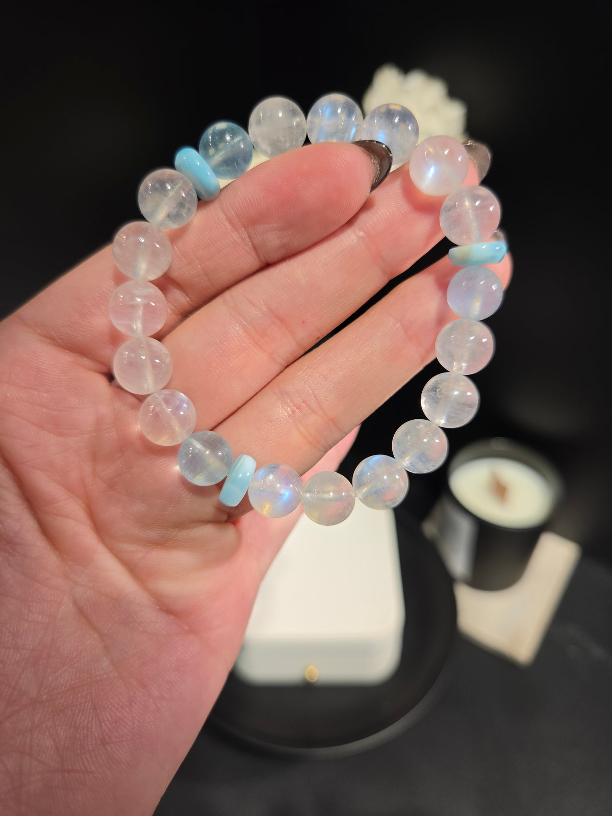 Hand holding light luxury blue sheen moonstone and aquamarine beaded crystal bracelet showing bead details