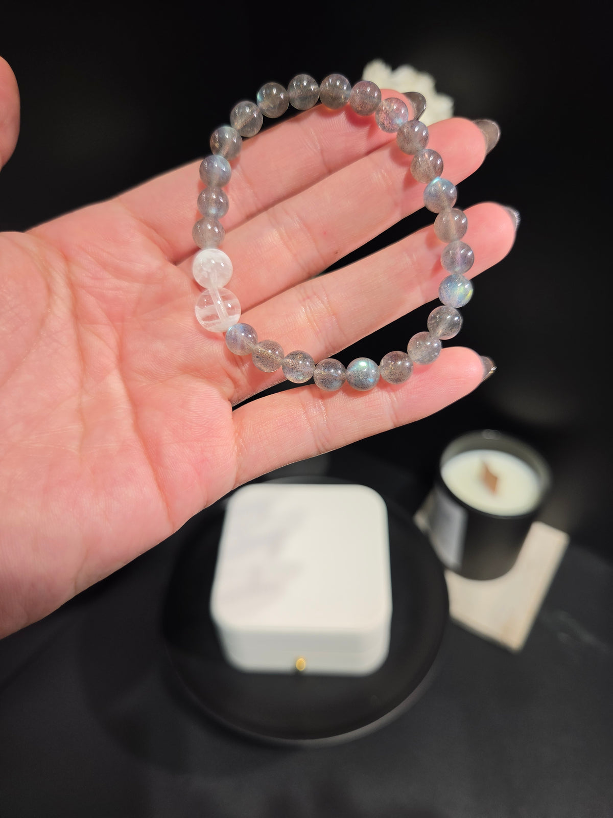 Light luxury labradorite and white moonstone beaded crystal bracelet held in hand showing flash